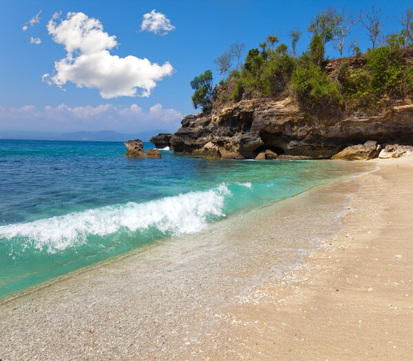 Вид с песчаного пляжа на скалы у океана. Индонезия, Бали
