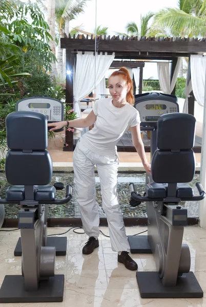 The young sporting woman in fitness center trains — Stock Photo, Image