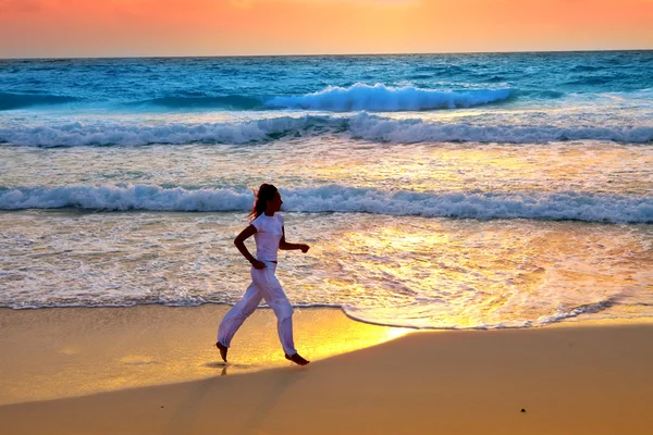 Mujer deportiva se dedica a correr en la costa del mar en una playa — Foto de Stock