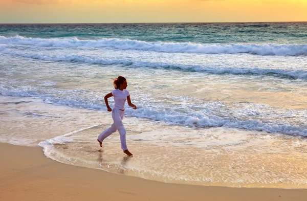 Spor kadın bir plaj deniz kıyısında koşarken devreye girer — Stok fotoğraf