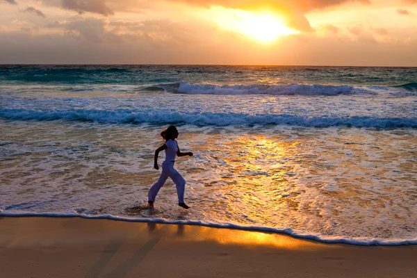 Silhueta de mulher, correndo ao pôr do sol ao longo da costa oceânica — Fotografia de Stock