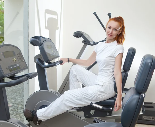 The young sporting woman in fitness center trains — Stock Photo, Image