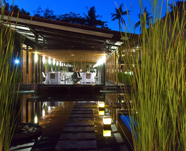 Mesas em um terraço aberto entre a natureza tropical à noite — Fotografia de Stock