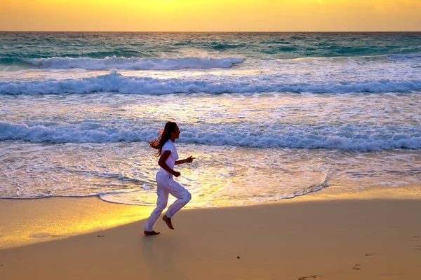 Mujer deportiva se dedica a correr en la costa del mar en una playa — Foto de Stock