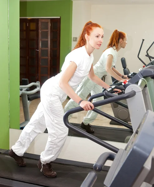 The young sporting woman in fitness center trains — Stock Photo, Image