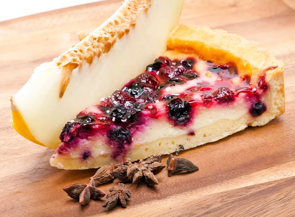 Cheesecake with berries and a fresh melon on a wooden tray — Stock Photo, Image