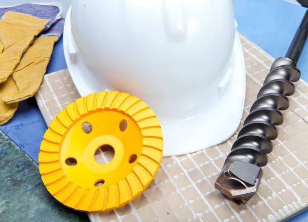 Der Bohrer, die Schleifscheibe für den Betrieb auf dem Beton, der Schutzhelm und die Arbeitshandschuhe — Stockfoto