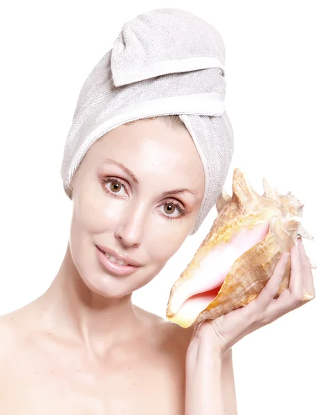 De mooie vrouw met een handdoek op het hoofd en een grote zee-cockleshell — Stockfoto