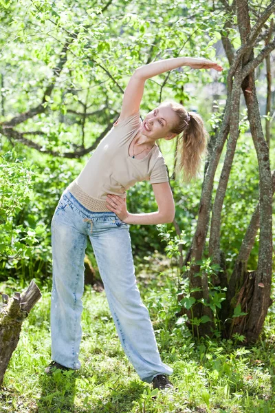 The young slender woman does sporting training in park — Stock Photo, Image