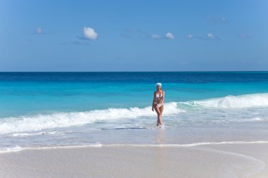 santa Claus şapka genç kadın bir plajda denize edg devam ediyor.