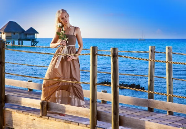 La joven hermosa mujer en un vestido largo en el camino de madera sobre el mar —  Fotos de Stock