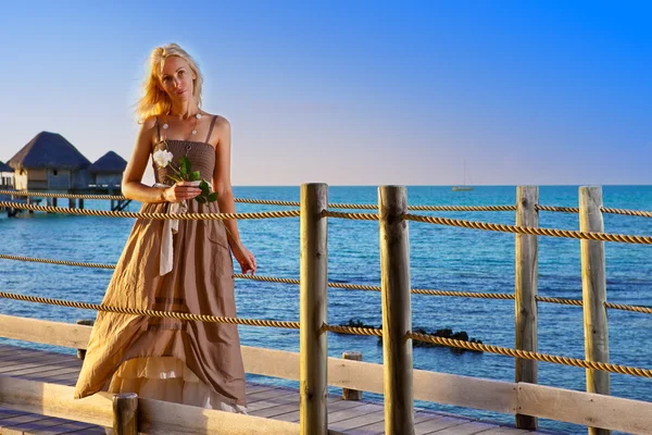 The young beautiful woman in a long dress on the wooden road over the sea — Stock Photo, Image