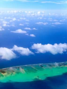 Polynesia. The atoll in ocean through clouds. Aerial view
