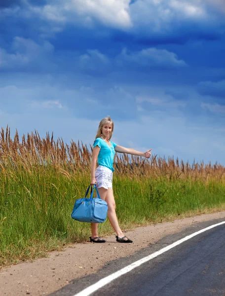 Hitchhiking girl votes on road — Stock Photo, Image