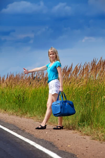 Hitchhiking girl votes on road — Stock Photo, Image