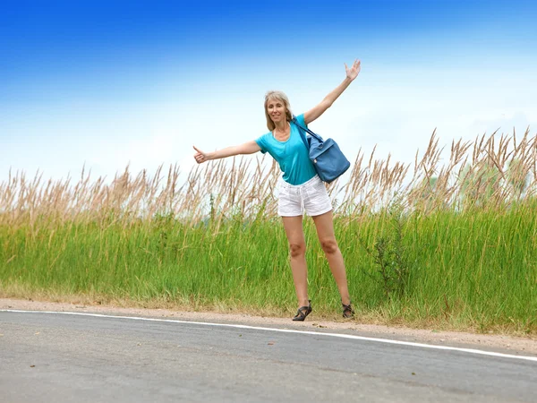 Hitchhiking girl votes on road — Stock Photo, Image