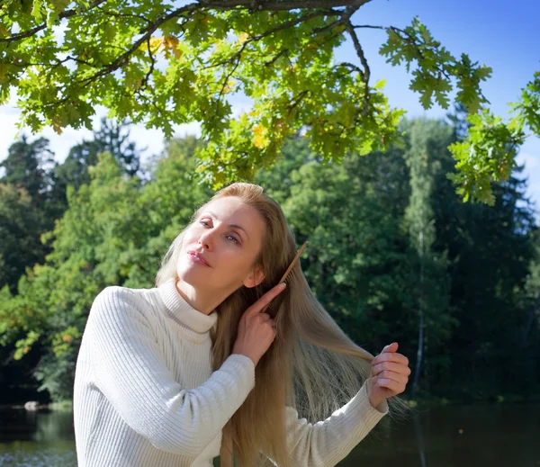 Schöne Frau kämmt lange Haare an einem Sommertag am Flussufer — Stockfoto