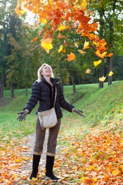 güzel bir kadın ile bir kucak dolusu akçaağaç sonbahar Park bırakır