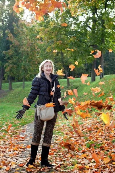 Красива жінка в осінньому парку з обладунками кленового листя — стокове фото