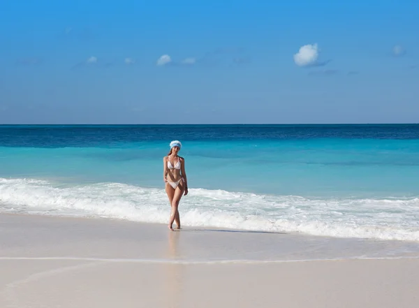 La giovane donna nel berretto dell'Anno nuovo cammina su una spiaggia — Foto Stock