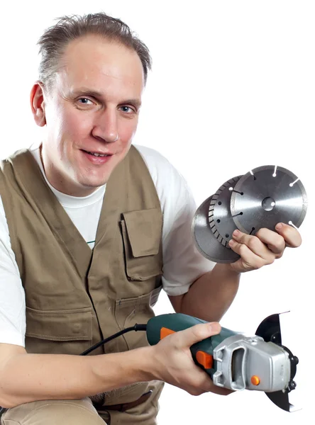O homem em macacão de trabalho com a máquina destacável e discos de serra — Fotografia de Stock