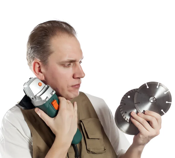 The man in working overalls chooses a detachable disk for the tool — Stock Photo, Image