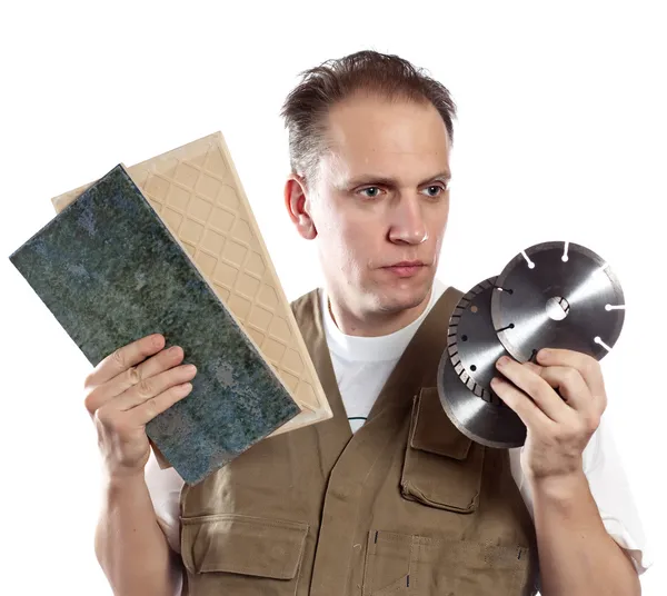 The man in working overalls chooses a detachable disk for the tool — Stock Photo, Image