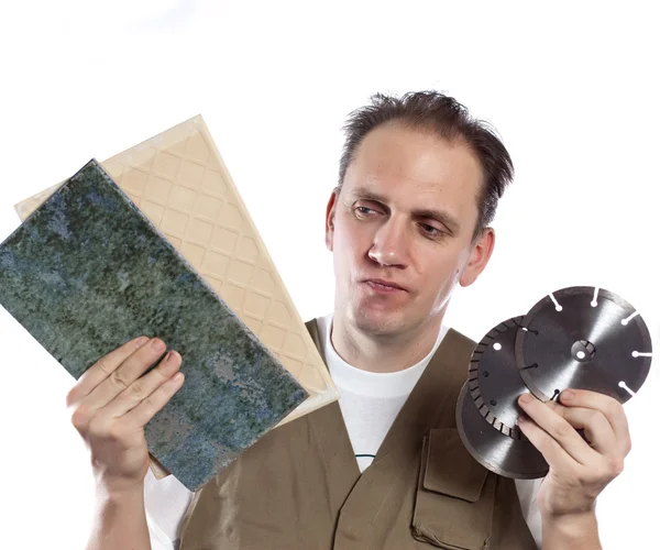 The man in working overalls chooses a detachable disk for the tool — Stock Photo, Image