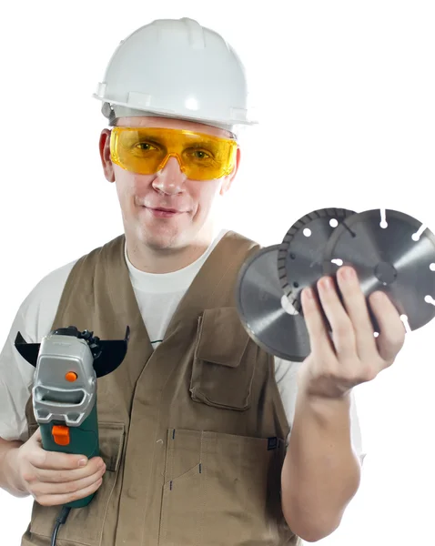 Человек в рабочем комбинезоне в очках и шлеме со съемной машиной и пилой — стоковое фото