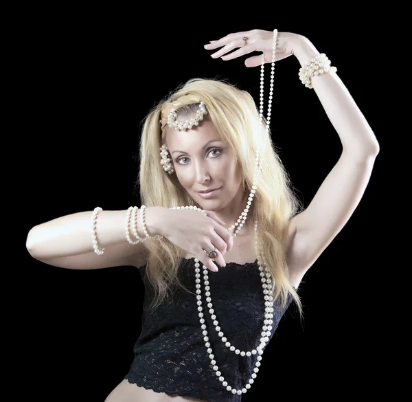 Bella giovane donna bionda con i capelli lunghi e una perla balla una danza orientale su sfondo scuro — Foto Stock