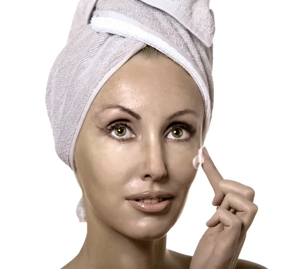 Красивая молодая женщина в полотенце с косметическим кремом — стоковое фото
