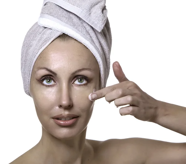 De mooie jonge vrouw in de handdoek met een cosmetische crème — Stockfoto