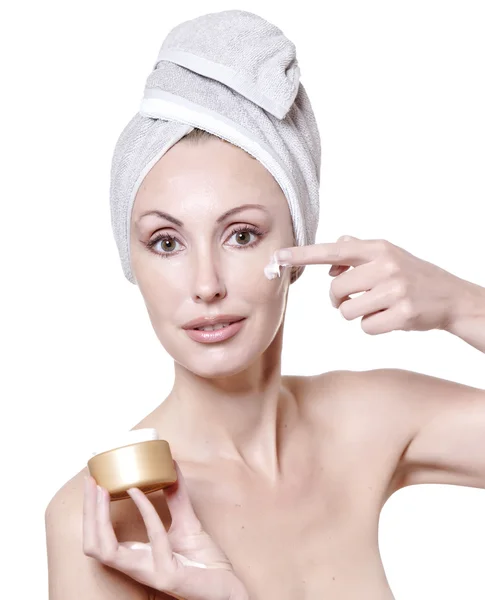 De mooie jonge vrouw in de handdoek met een cosmetische crème — Stockfoto