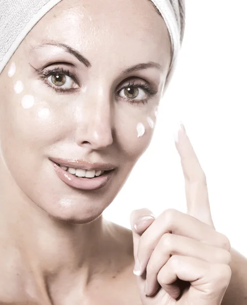 De mooie jonge vrouw in de handdoek met een cosmetische crème — Stockfoto