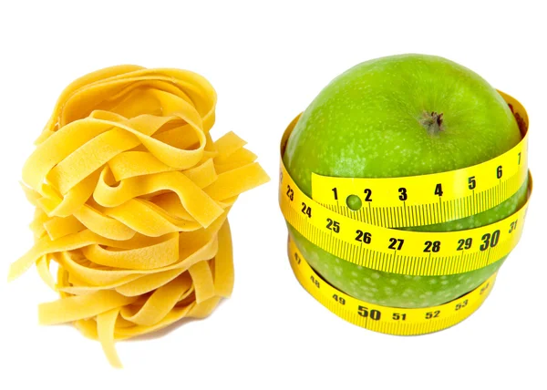 Macarrão ninho fettuccine italiano e maçã com uma fita métrica — Fotografia de Stock