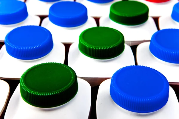 Dairy products bottles stand in rows, bright covers — Stock Photo, Image