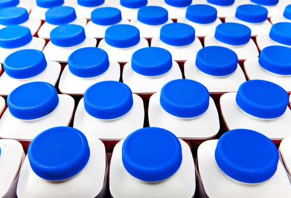 Produkty mleczne butelki stoją w rzędach, jasne pokrywy — Zdjęcie stockowe