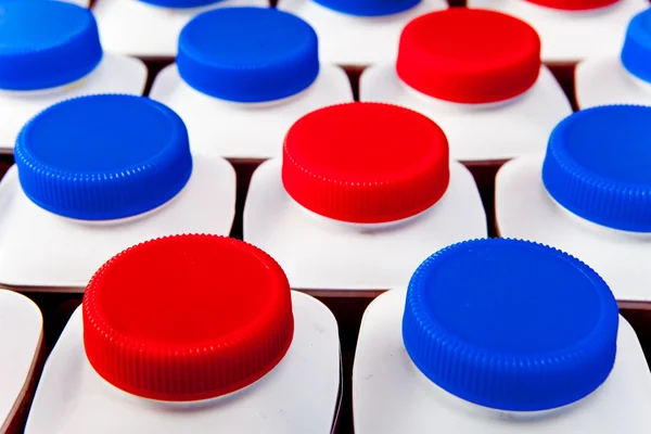 Produkty mleczne butelki stoją w rzędach, jasne pokrywy — Zdjęcie stockowe