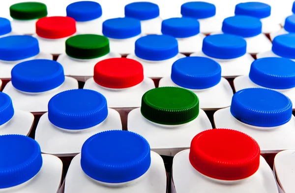 Dairy products bottles stand in rows, bright covers — Stock Photo, Image