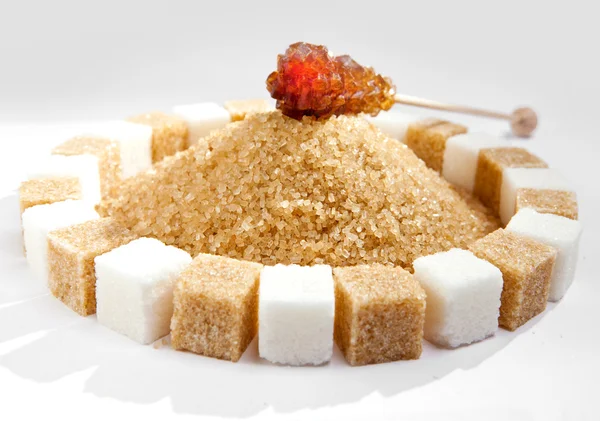Kostky cukru leží na kruhy a cukr kandys na špejli na hromadu krystalového cukru uvnitř — Stock fotografie