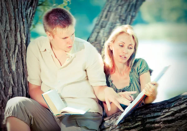 Joven chico y chica con libros sobre la naturaleza cerca del lago, con un efecto retro — Foto de Stock