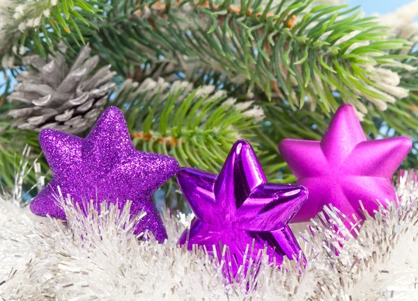 Три пурпурных снежинки на фоне новогодних ветвей — стоковое фото