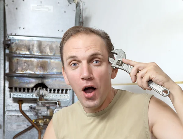 L'uomo con una chiave inglese pensa a riparazione di uno scaldabagno a gas — Foto Stock