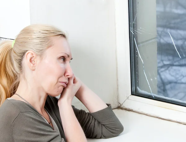 La triste joven cerca de una ventana con el vidrio roto — Foto de Stock