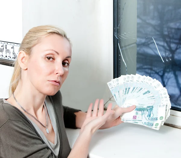 Den sorgliga unga kvinnan räknas pengar för fönster reparation med burst, glaskross — Stockfoto