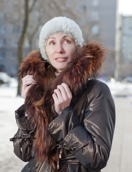 A jovem mulher em uma jaqueta com um colarinho de pele na rua no inverno — Fotografia de Stock