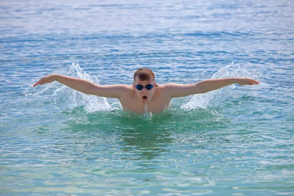 Young sporting man swims in the sea butterfly stroke style. — Stock Photo, Image