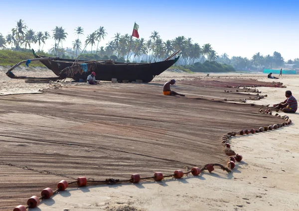 GOA, INDIA - 01 DE FEBRERO: pescador repara redes de pesca después de la pesca de la mañana en 01 de febrero 2014 en Goa, India —  Fotos de Stock