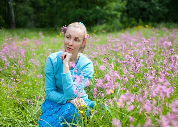 A jovem feliz no campo das flores silvestres — Fotografia de Stock