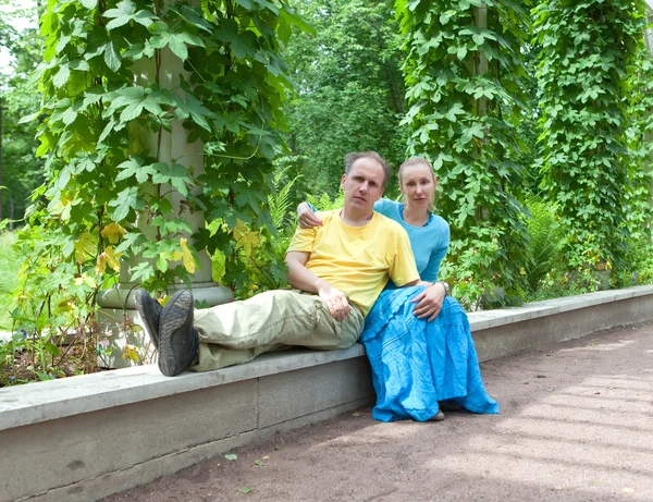 Jeune couple heureux assis dans les verts torsadés de tonnelle — Photo